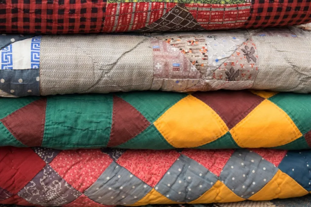 a folded stack of muted color quilts.
