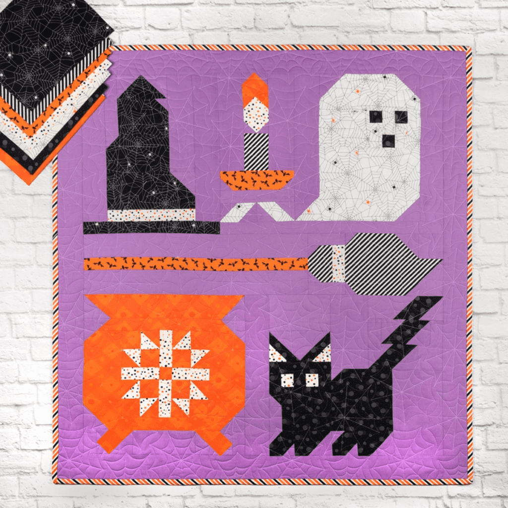 A quilt with a witch's hat, ghost, cauldron and black cat.