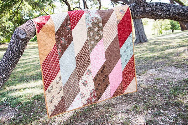 A fat eighth quilt hanging off of a branch.
