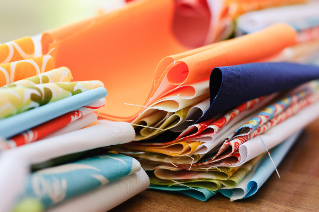 stacks of colorful fabric lined up on a table.